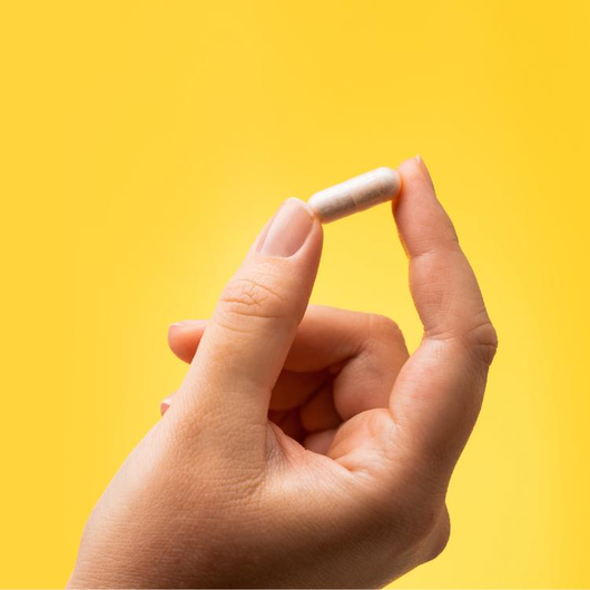 A single Kiro Dopamine capsule held between finger and thumb